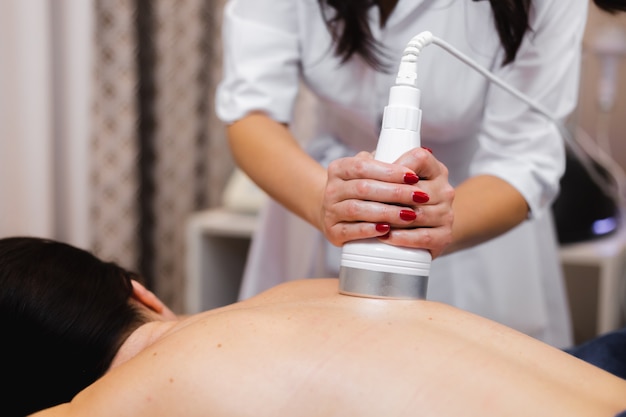 The girl in the spa salon receives a back and neck massage, lies in the cosmetology table, relaxed and enjoys the process