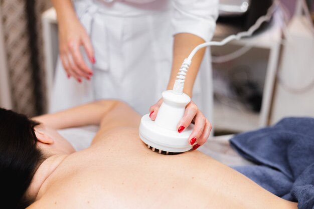 The girl in the spa salon receives a back and neck massage, lies in the cosmetology table, relaxed and enjoys the process
