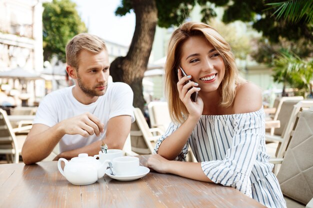 Girl speaking on phone while her boyfriend being bored.