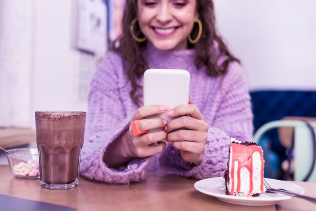 ライブラリに電話で話しているコーヒーと魅力的な若いブルネットの女性 コーヒーブレイク 大学生活 現代の仕事 勉強 賢い学生 いい仕事 無料の写真