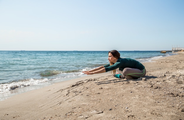 Девушка в спортивной фитнесе на берегу моря, слушает музыку, спортивная мотивация, спорт, фитнес