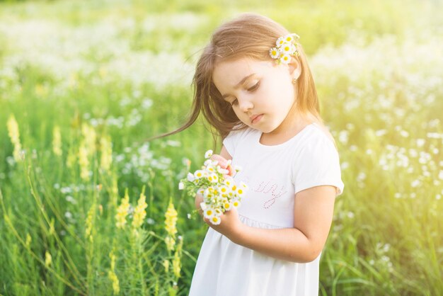 Girl standing in the field looking at white flowers