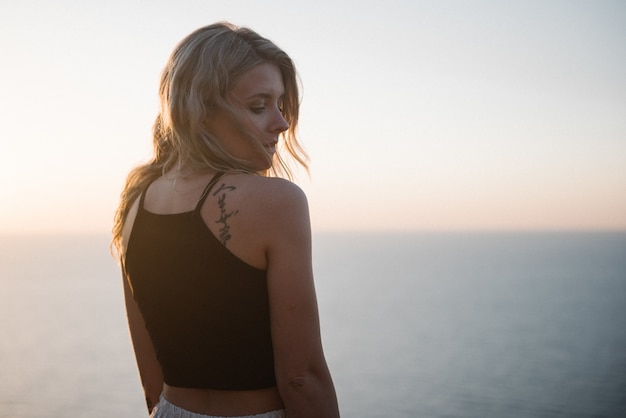 Free photo girl standing in front of a sunset smiling