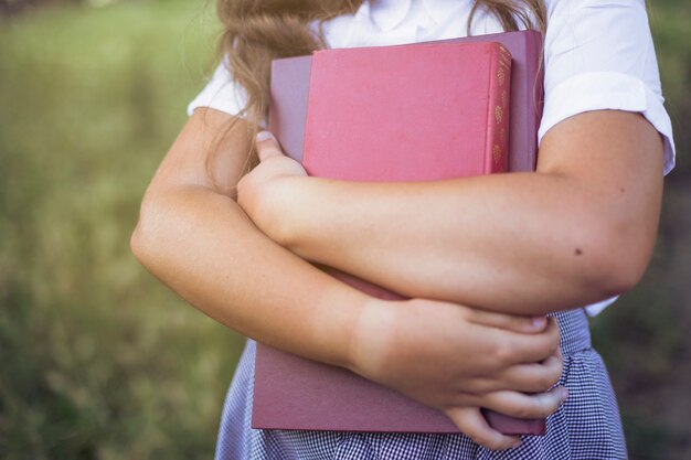 Girl standing holding books in arms