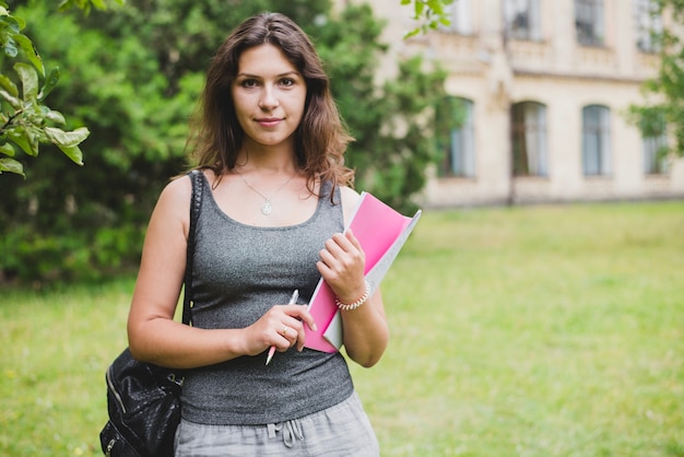 Girl standing holding notebook pencil smiling