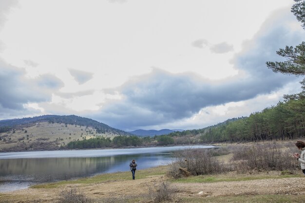 遠くに山の風景とピバ湖（Pivsko jezero）の近くに立っている女の子