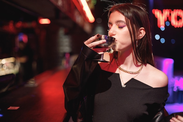 Girl standing in a night club with colorful bright neon red lights