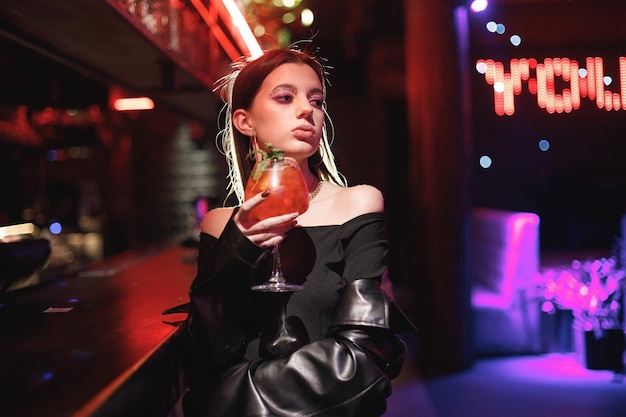 Girl standing in a night club with colorful bright neon red lights