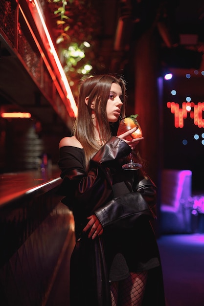 Girl standing in a night club with colorful bright neon red lights