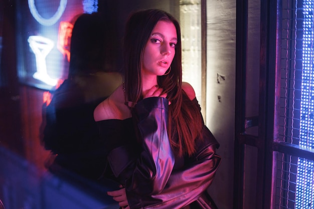 Girl standing in a night club with colorful bright neon red lights