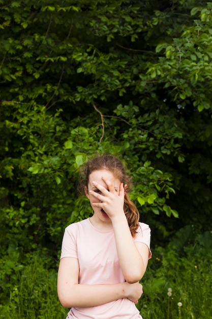 Foto gratuita ragazza che sta nel parco che dà una occhiata tramite il suo dito