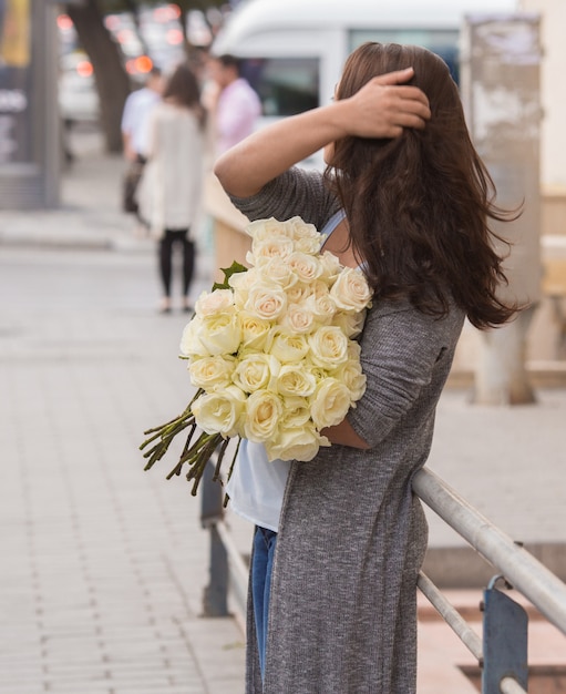 Girl standing in the street with a bouquet of white roses