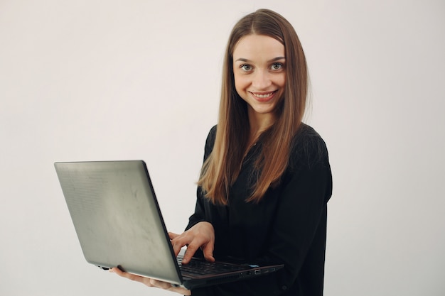 Girl standing on a white wall with a laptop
