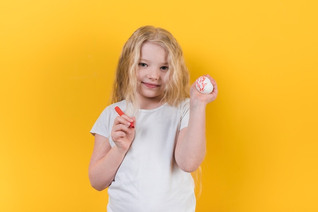 Girl standing with painted egg and felt pen