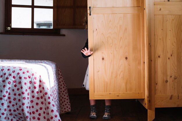 Girl standing behind wooden cupboard