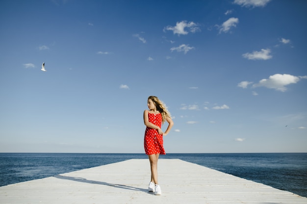 a girl stands on a berth and looks at sea