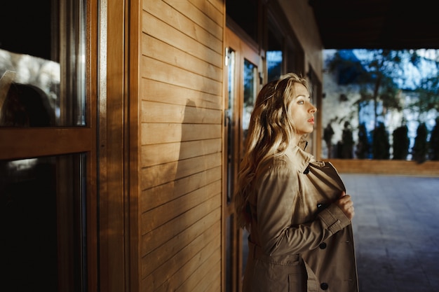 a girl stands sideway near a wall and looks into the distance