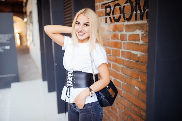 A girl stands at a wall of red bricks outdoors