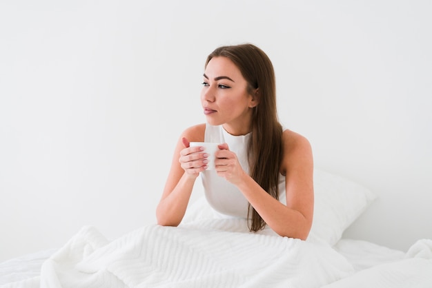 Girl staying in bed and drinks coffee