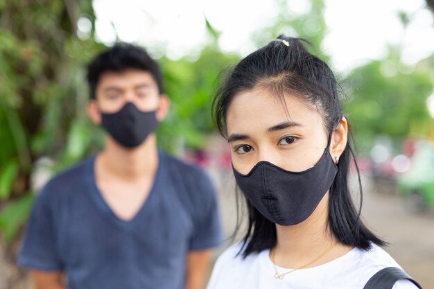 Девушка на улице надевает маску для лица, чтобы предотвратить вирус и противостоять дымке.