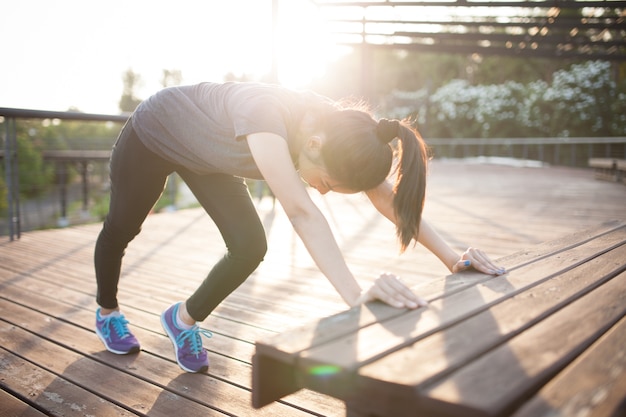 Girl stretching with a wooden bench