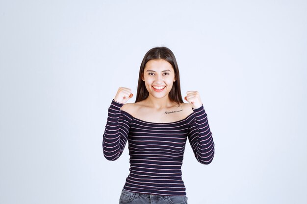 Foto gratuita ragazza in camicia a righe che dimostra i suoi muscoli del braccio.