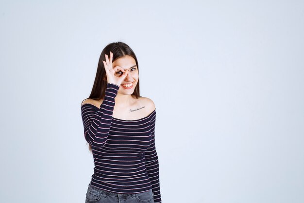 Ragazza in camicia a righe facendo segno di godimento.