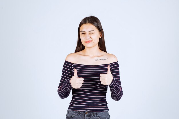 Girl in striped shirt doing enjoyment sign. 