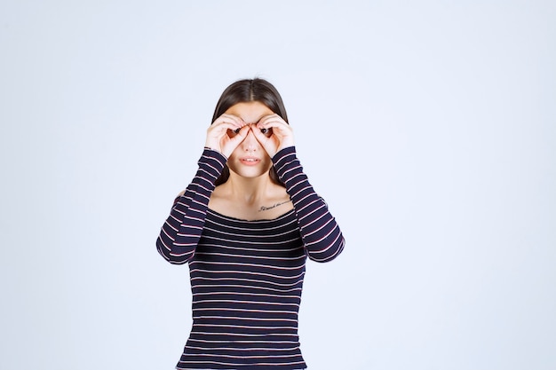 Free photo girl in striped shirt looking through her fingers.