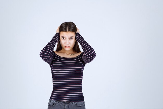 Free photo girl in striped shirt looks confused and thrilled.