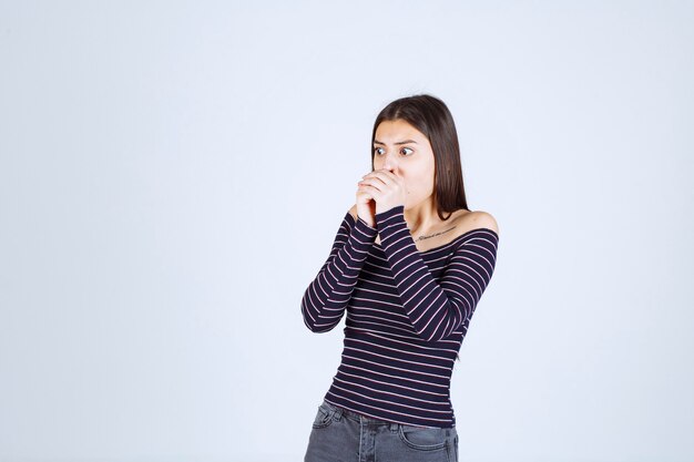 Girl in striped shirt looks terrified and scared. 