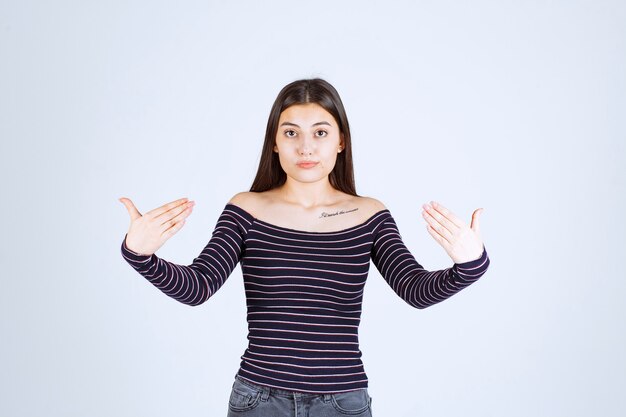 Free photo girl in striped shirt pointing at herself.