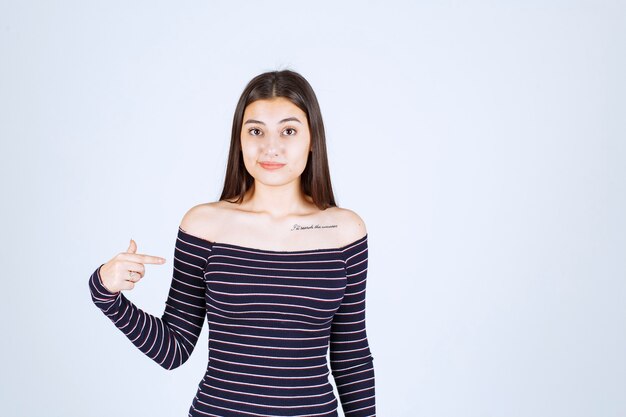 Girl in striped shirt pointing at herself. 