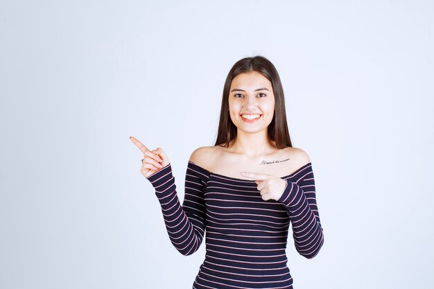 Girl in striped shirt pointing to the side. 