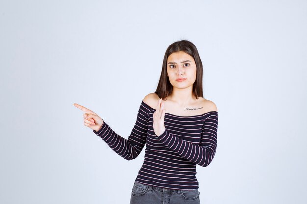 Girl in striped shirt pointing to the side. 