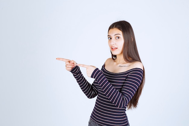 Girl in striped shirt pointing to the side