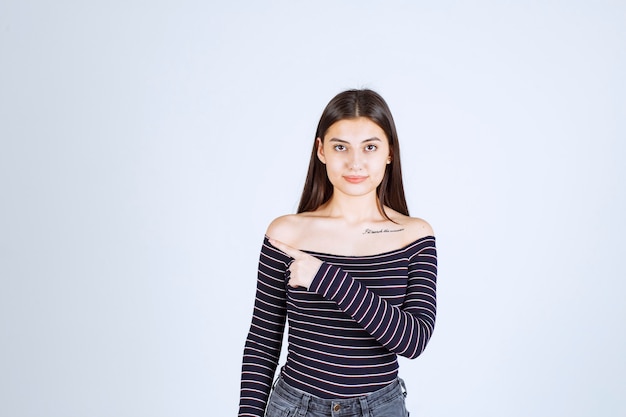 Girl in striped shirt pointing at somebody on the left side. 