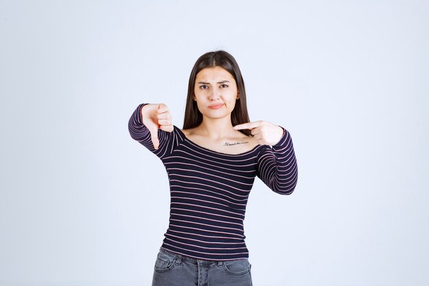 Girl in striped shirt pointing at somebody on the left side. 