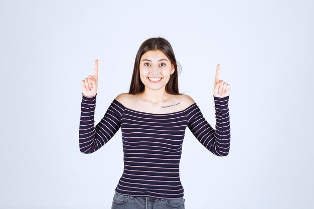 Girl in striped shirt pointing up and showing emotions. 