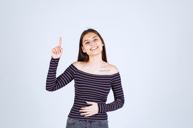 Girl in striped shirt pointing up and showing emotions. 