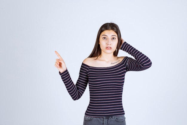 Girl in striped shirt pointing up and showing emotions. 