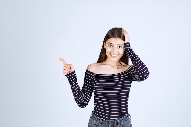 Girl in striped shirt pointing above. 