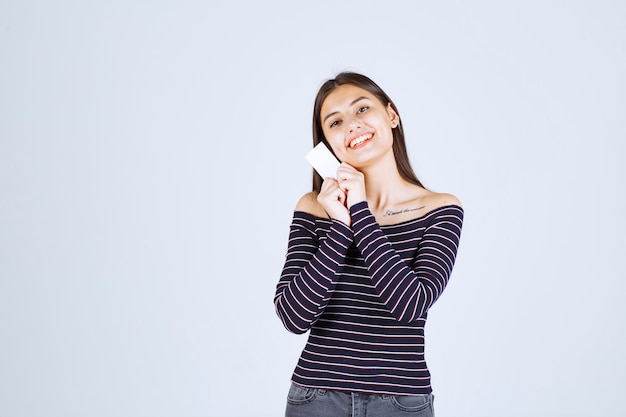 Girl in striped shirt presenting her business card with a confidence.