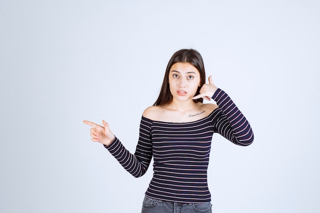 Ragazza in camicia a righe che mostra il segnale di chiamata.