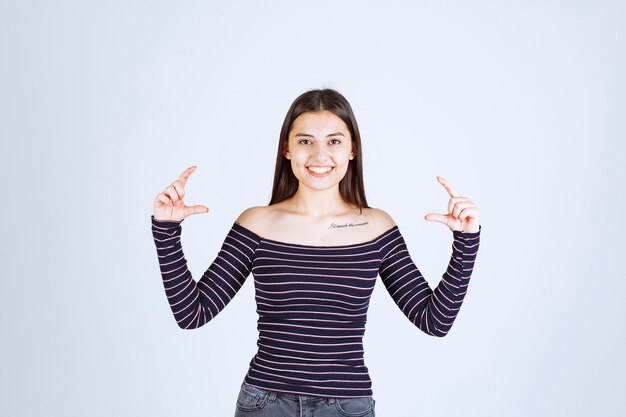 Girl in striped shirt showing the estimated measure or amount of a product. 