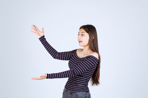 Girl in striped shirt showing the estimated measure or amount of a product. 