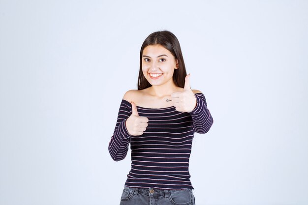 Girl in striped shirt showing good enjoyment sign. 