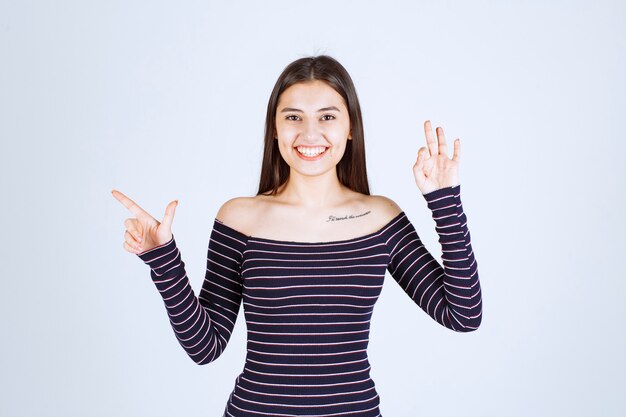 Girl in striped shirt showing good enjoyment sign. 