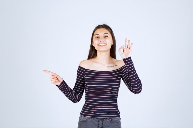 Girl in striped shirt showing good enjoyment sign. 