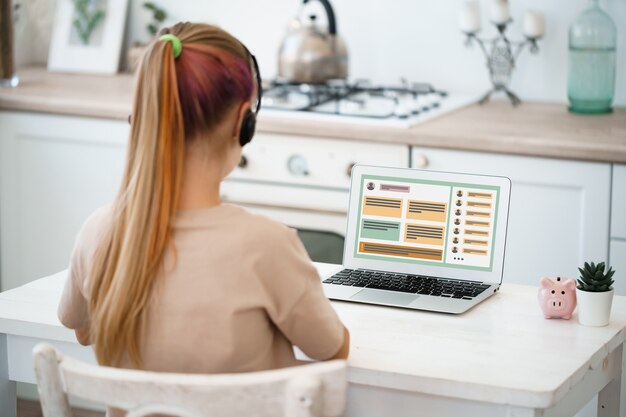 Девушка-студентка обучается на дистанционном обучении дома на ноутбуке